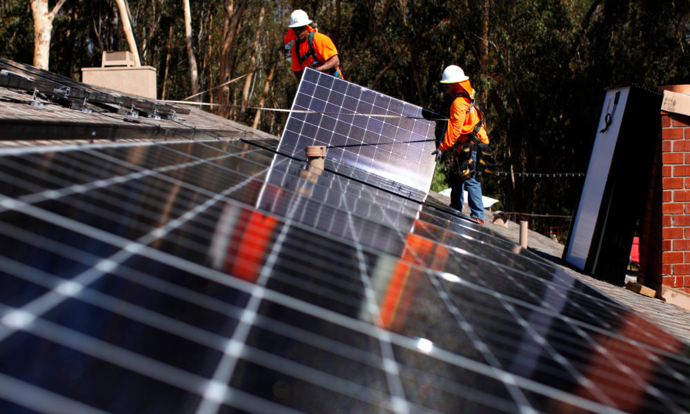 Solar installers from Baker Electric place solar panels on the roof of a residential home in Scripps Ranch, San Diego, California, U.S.