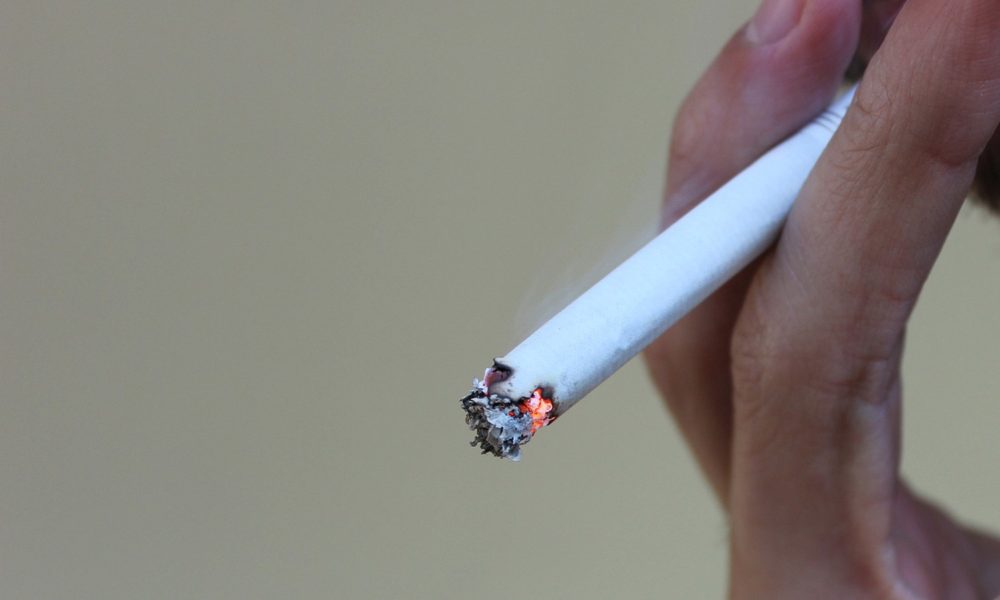 Closeup view of a lit cigarette in a person's hand