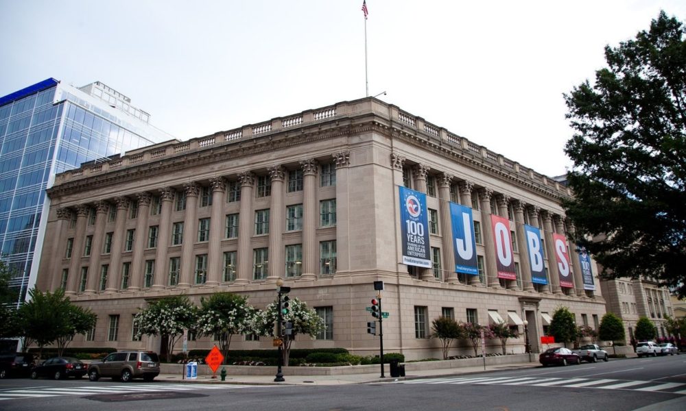 the exterior of the US Chamber of Commerce, shot from across the street. a large banner celebrates quote, 100 years of American enterprise, unquote, and another spells out, "jobs"