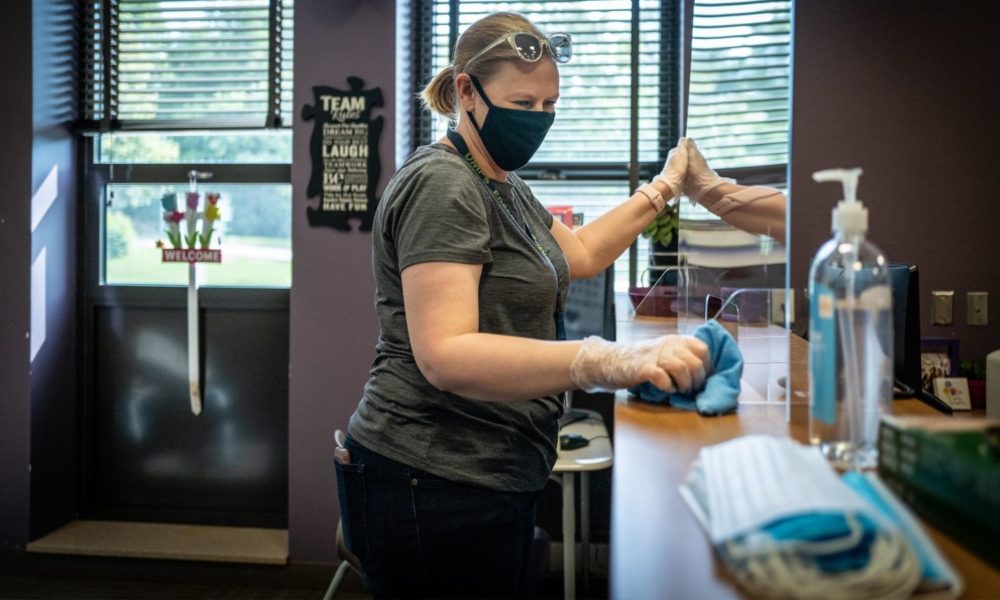 A worker sets up a plexiglass divider in an elementary school office in a Des Moines school as they prepared for a limited return to school in 2020.