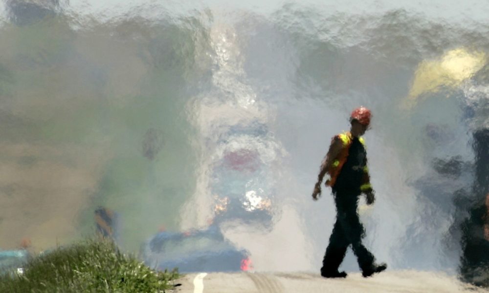 A road worker walks across the road during a road recycling project on US 183 south of Rush Center, Kan. The heat behind the worker is so intense, there's a blurring effect in the background.