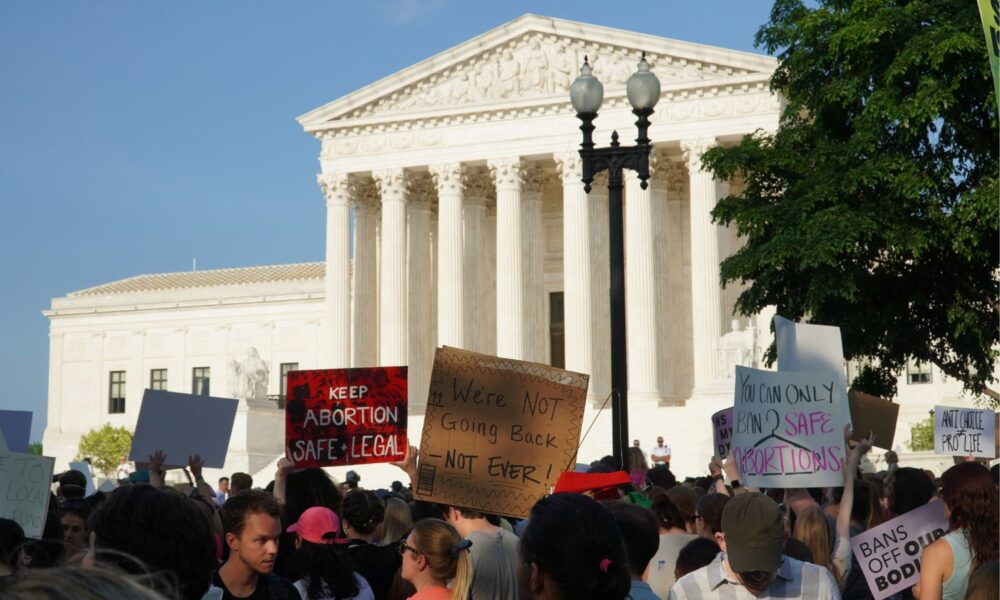 Photo from an abortion rights protest in front of the Supreme Court from May 2022. A sign reading "we are never going back" is visible.