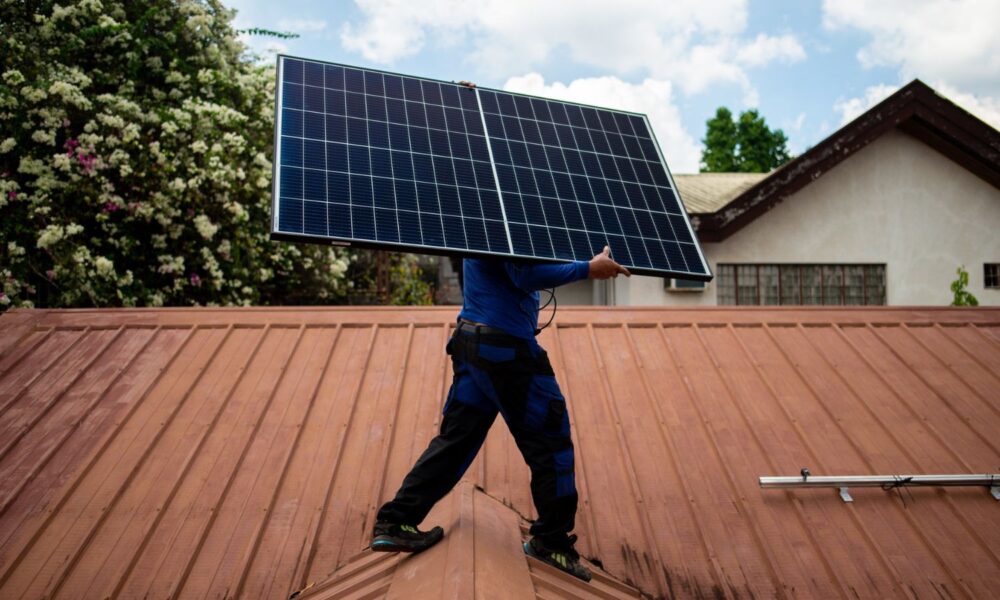 A worker from PHILERGY, a German-Filipino supplier and installer of solar energy, carries a solar panel during a home installation.