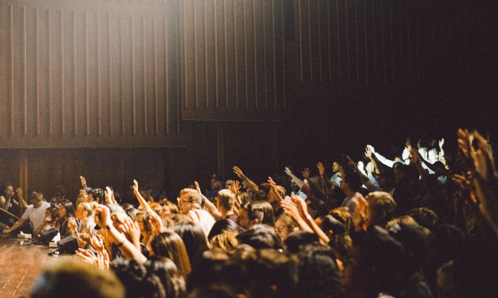 Students in a lecture hall raising their hands