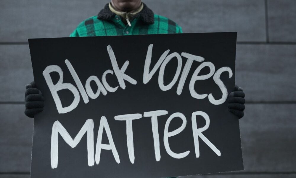A man holding a sign that reads, "Black Votes Matter"