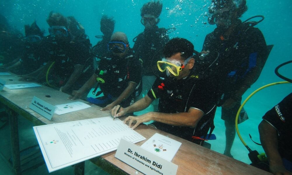 Maldives Minister of Fisheries and Agriculture Dr Ibrahim Didi signs the decree of underwater cabinet meeting.