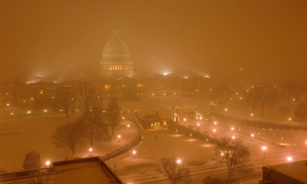 A view of the US Capitol building in a snowstorm, through the haze of yellowish streetlights