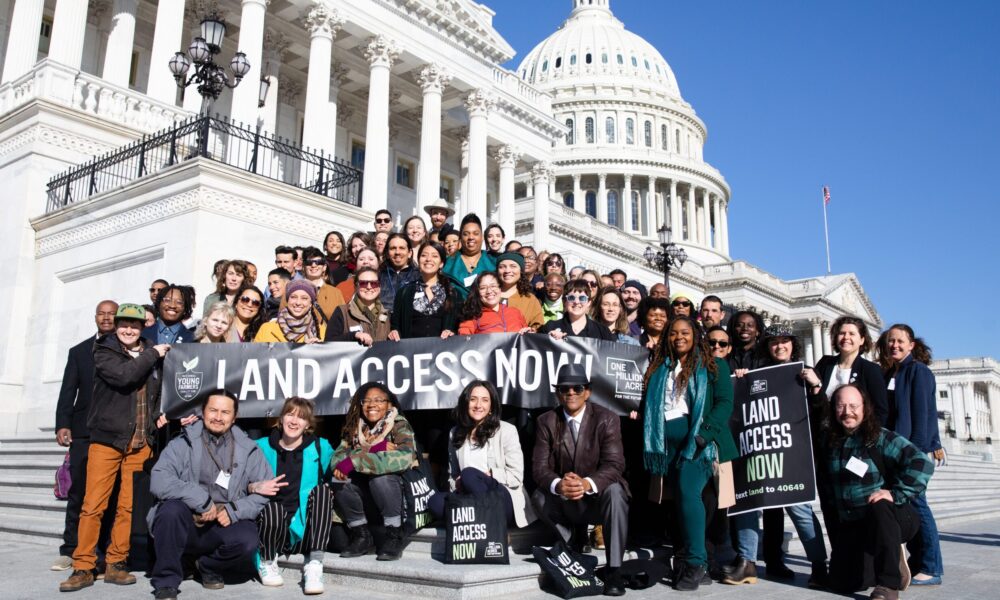 photo of a large group of people posed at the base of the US Capitol's steps, with the dome behind them, holding a banner that reads "Land Access Now"
