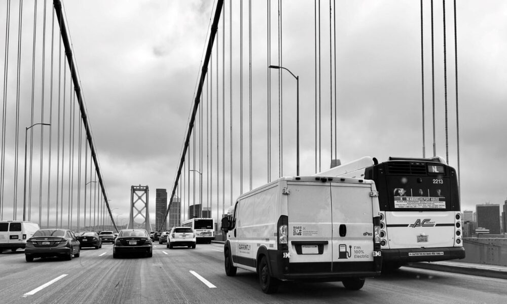 A white electric van drives towards San Francisco on the Oakland Bay Bridge in California.