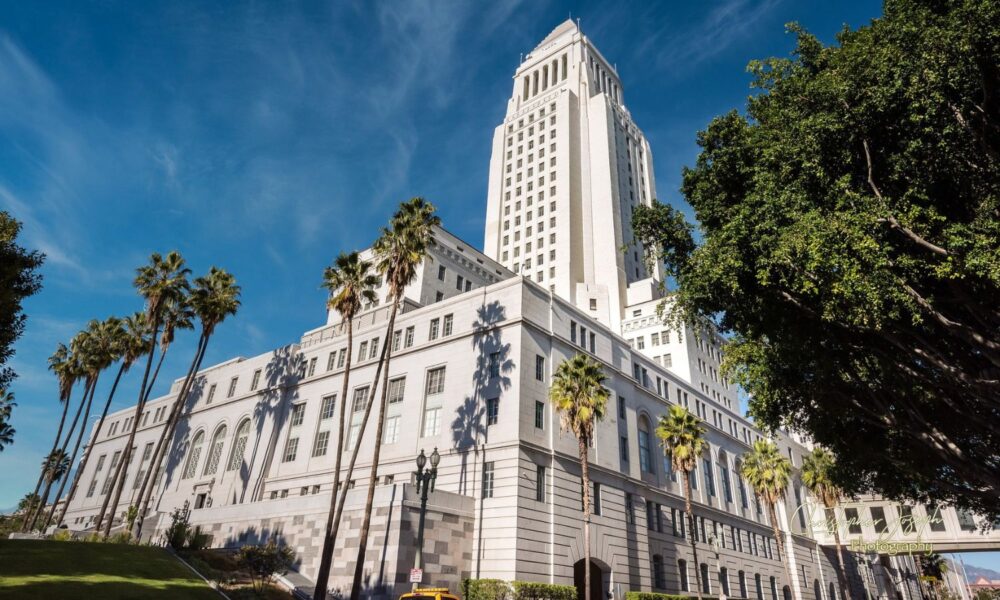 Los Angeles City Hall, an imposing art deco-style building, surrounded by blue skies and palm trees.