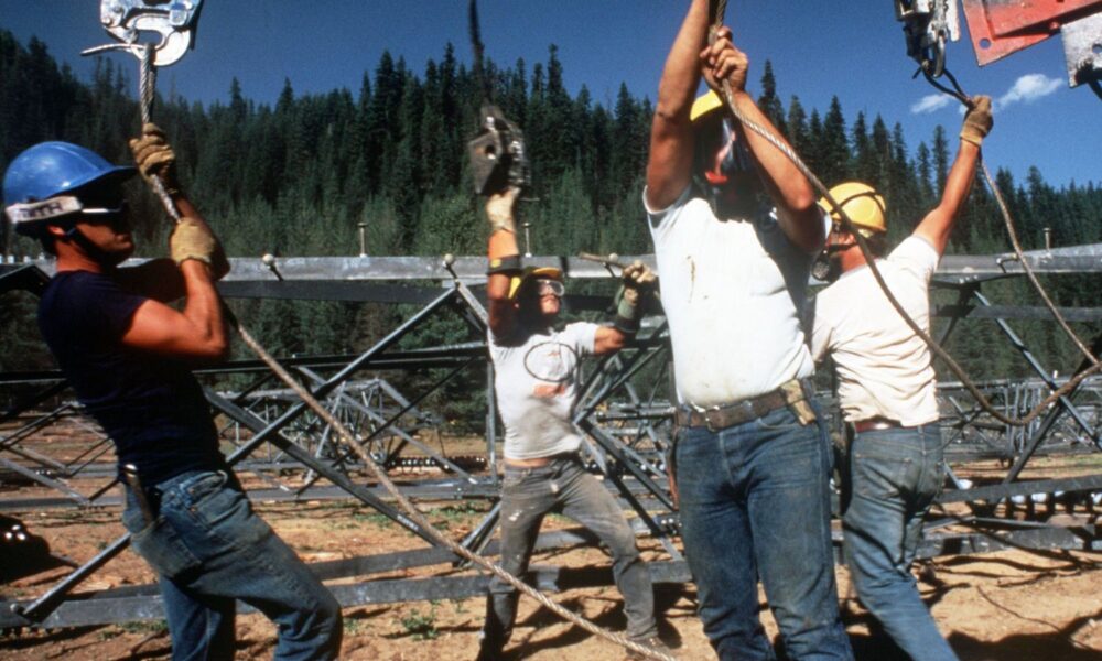 Four men work together on the construction of a transmission tower, part of the Bonneville Power Administration in the US Pacific Northwest.