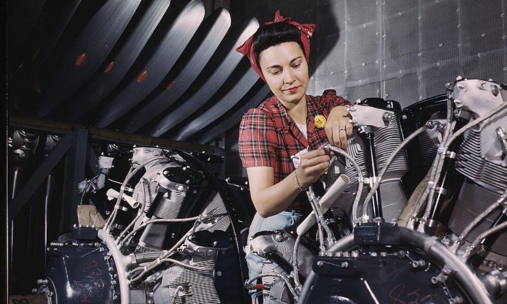A real-life 'Rosie the Riveter': a woman wearing a Rosie-style bandana works on an airplane motor at North American Aviation, Inc., plant in California.