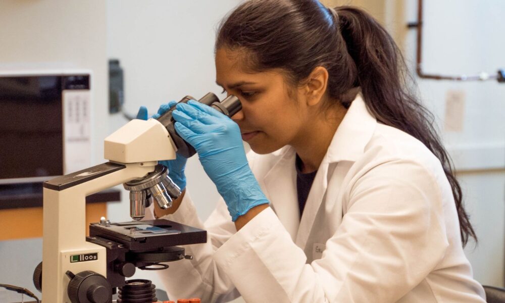 Woman scientist looking through microscope