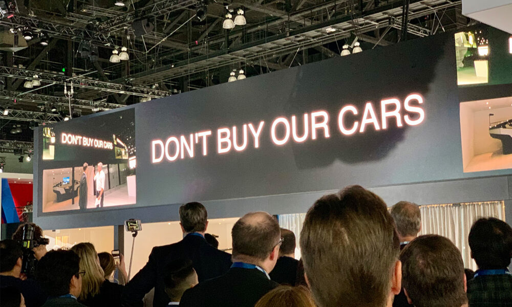 A large banner reading "Don't Buy Our Cars" hangs over the crowd at the LA Auto Show. (It was a message from automaker Volvo, suggesting buyers should lease their cars instead)