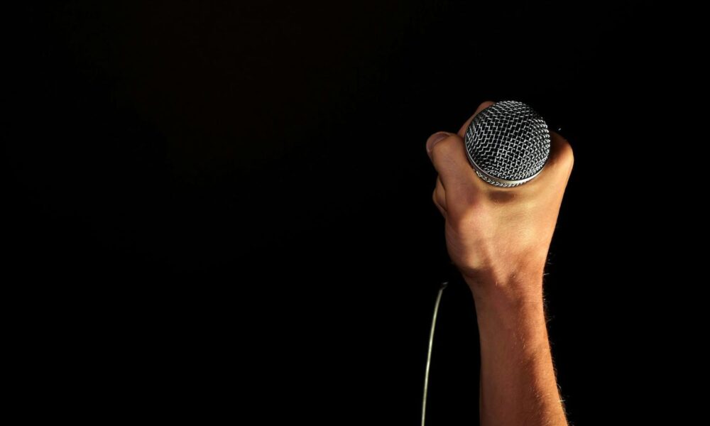 hand holding microphone on black background