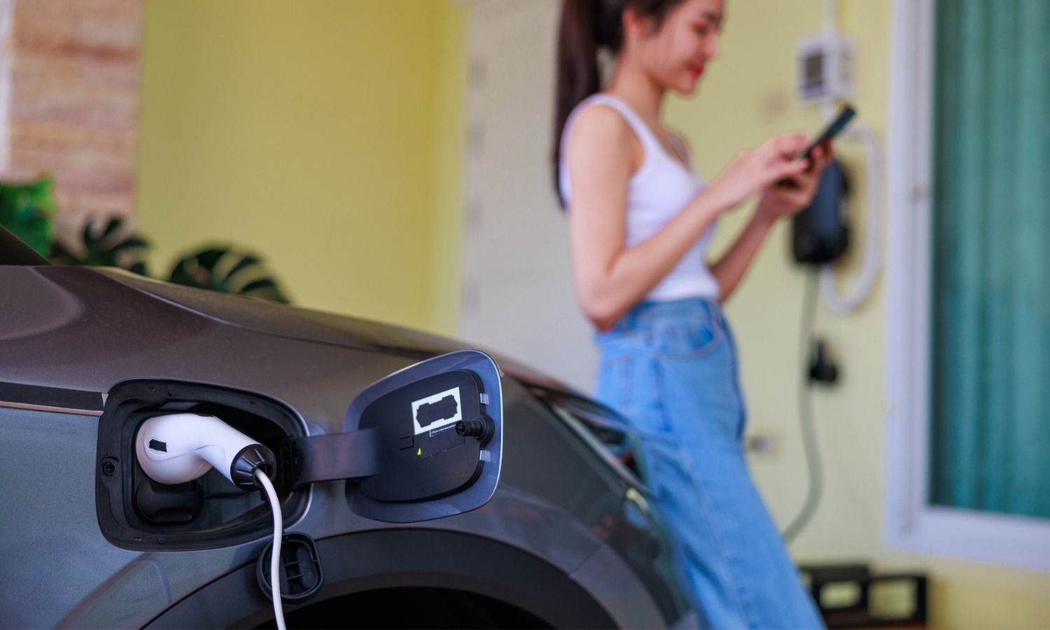 Woman Plugs in Electric Charger for Car at Home