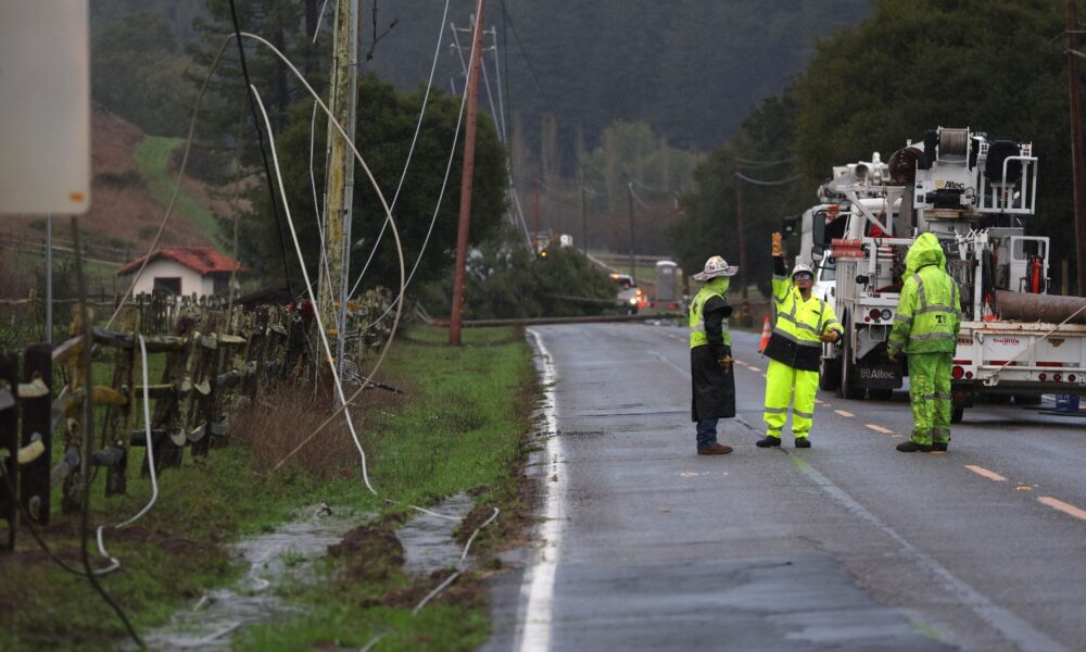 Utility workers prepare to make repairs to downed power lines on Nicasio Valley Road after utility poles were toppled by high winds on January 05, 2023, in Nicasio, California. A powerful storm pounding the West Coast uprooted trees and cut power for tens of thousands on the heels of record rainfall that month.