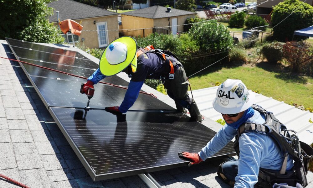 GRID Alternatives employees install no-cost solar panels on the rooftop of a low-income household in October 2023 in Pomona, California.