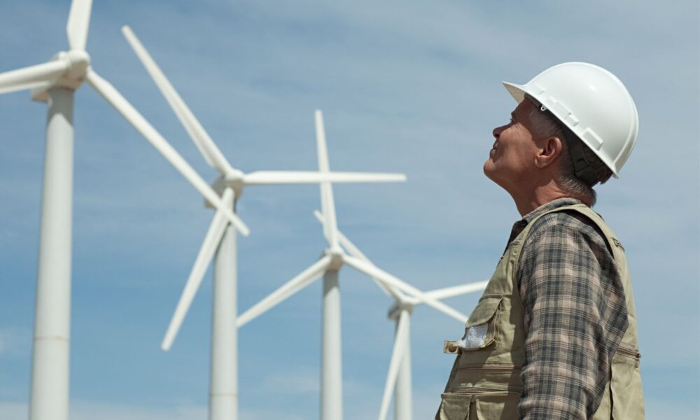 Man in hard hat looking at wind turbines.