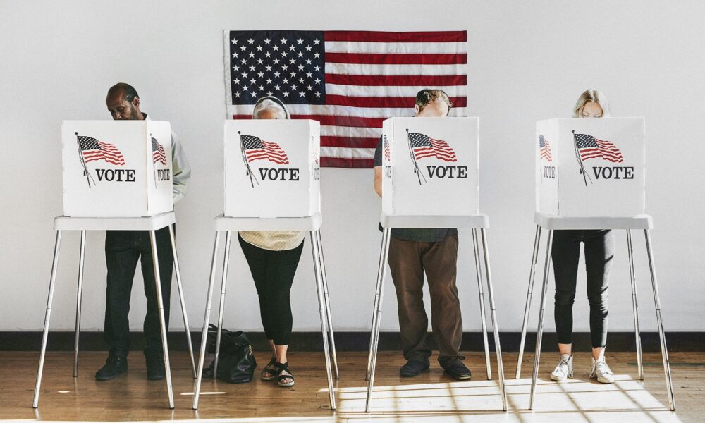 voters casting ballots with US flag in background