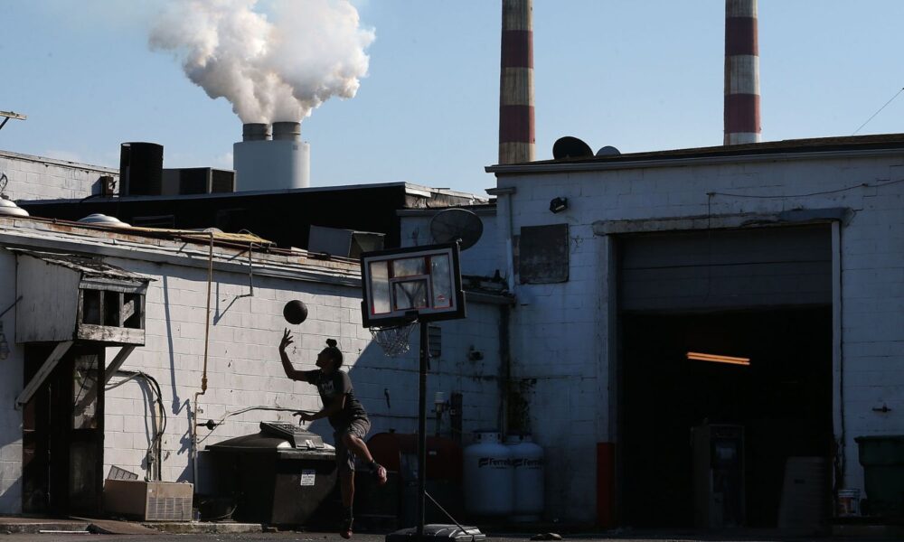 A young person plays basketball behind a truck stop restaurant as emissions spew out of a large stack nearby at the coal-fired Morgantown Generating Station on the Potomac River in Newburg, Maryland.