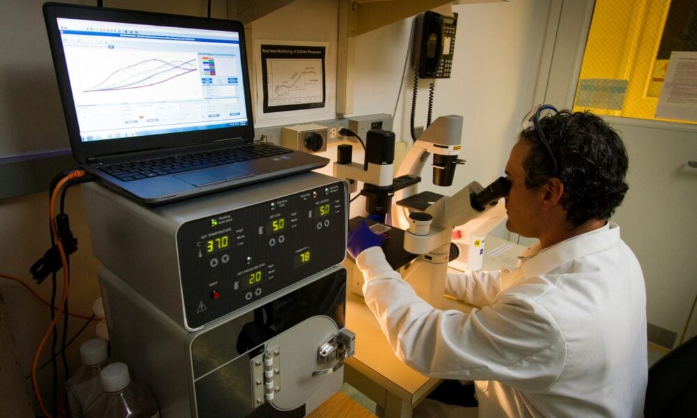 A man looking through a microscope in a lab.