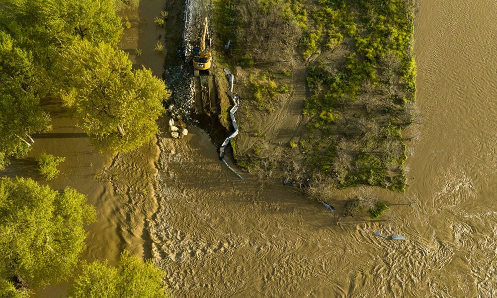 excavator placing large rocks to close a levee break caused by flood waters from the Pajaro River near the township of Pajaro in Monterey County, California.